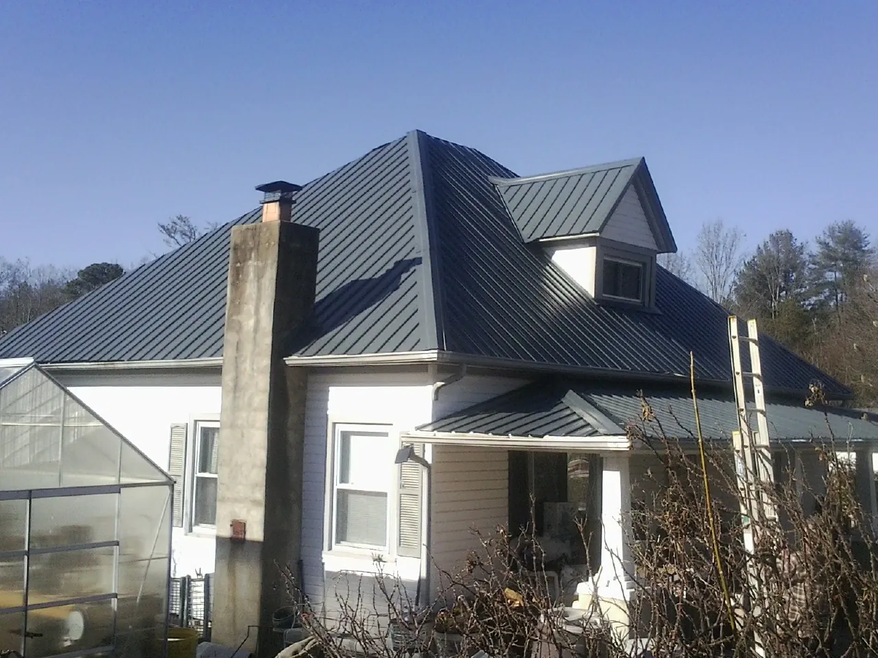 Dark blue standing seam metal roof on a white farmhouse with dormer — Slate & Tile Roof Repair by Roofing Brothers in Walpole