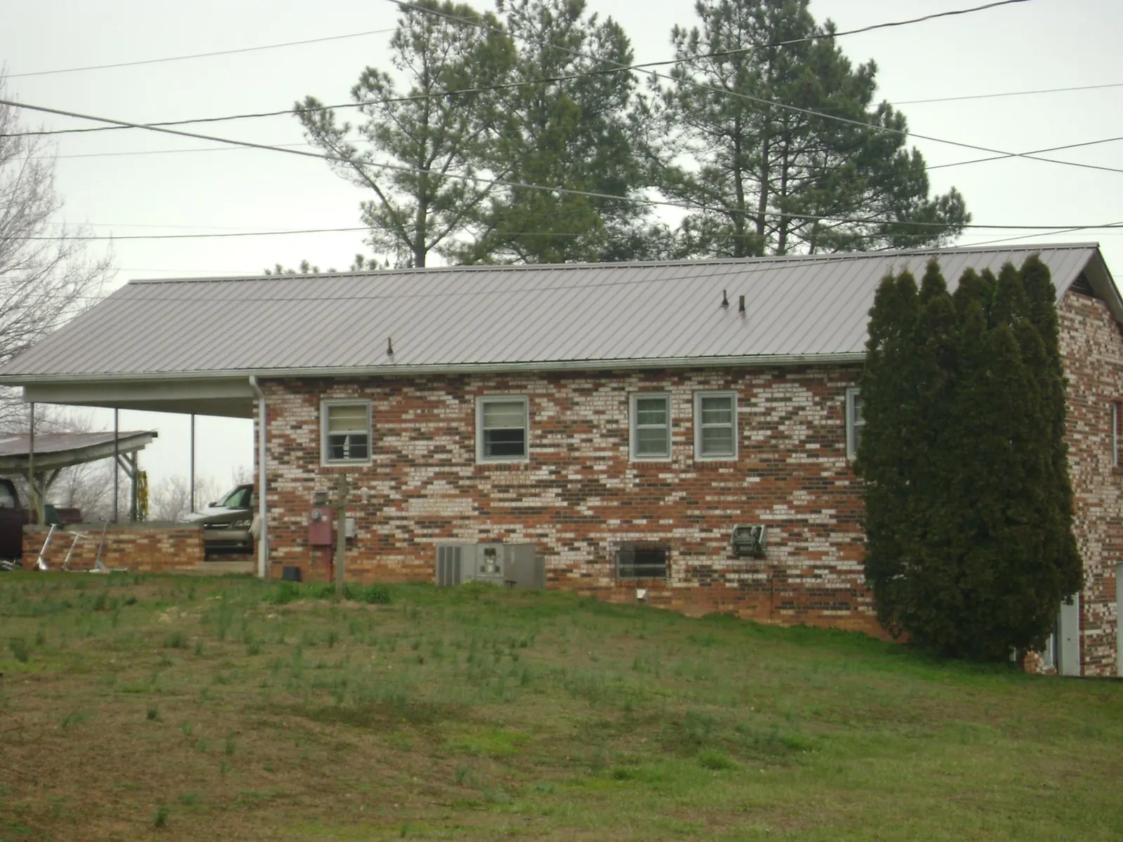 Gray metal roof on a brick split level home with a carport in Walpole