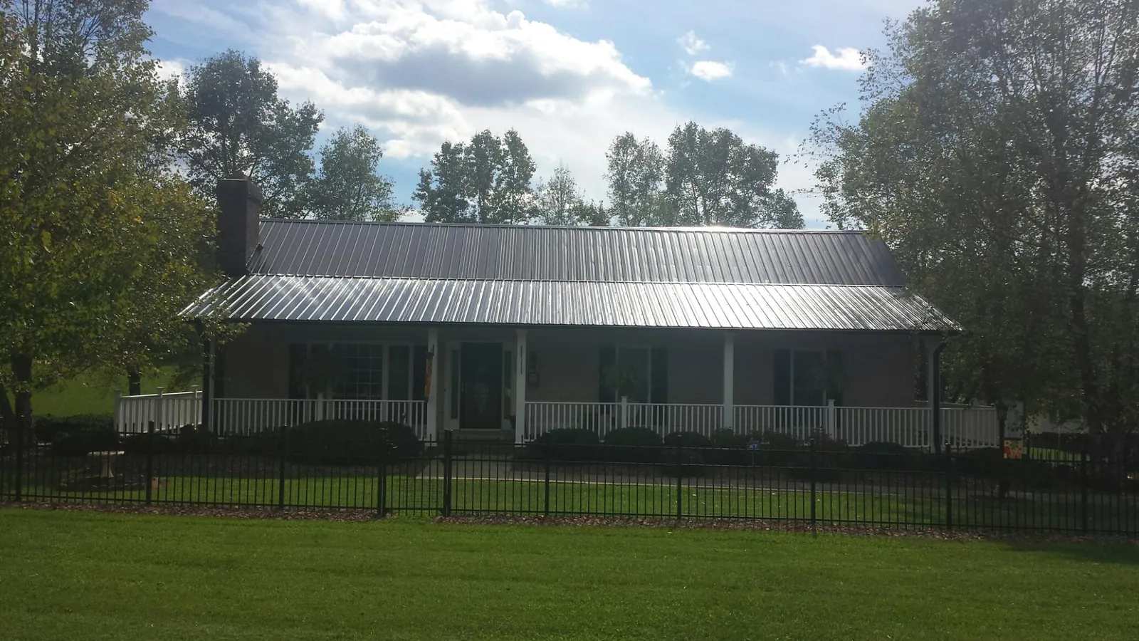 Gray metal roof on a brick ranch with a full width front porch — Gutter Guard Installation work by our crew in Walpole
